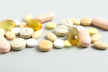 Various pills and capsules on gray background