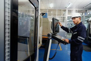 Factory engineer setting and programing to start CNC machine in the manufacturing. Male worker...