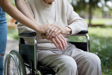Close-up of an elderly person's hands on a wheelchair armrest with supportive touch