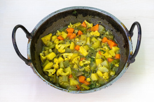 A Karahi of mixed vegetables, including cauliflower, carrots, beans, snake gourd, potatoes, pointed gourd, and cucumbers. Healthy diet concept.