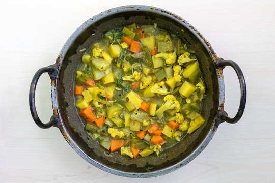 A Karahi of mixed vegetables, including cauliflower, carrots, beans, snake gourd, potatoes, pointed gourd, and cucumbers. Healthy diet concept. Top view.