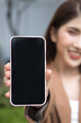 Fast Connectivity for young people, young adult happy smiling Asian business woman hand holding Smartphone with blank black screen, concept of Technology in Urban Life in workplace