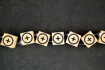 a wooden square with a plus or plus icon connected by a line. + Characters. plus. Addition. gain.