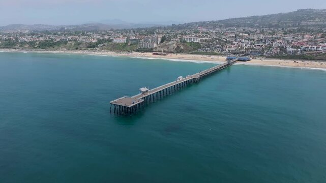 Aerial video of San Clemente pier from ocean toward coastline