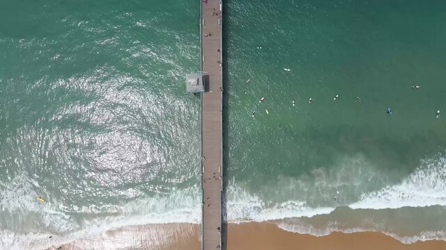 Overhead view of San Clemente pier and surfers in water