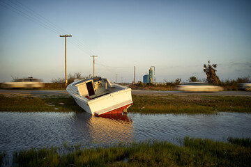 A derelict fishing boat sits partially submerged in water.