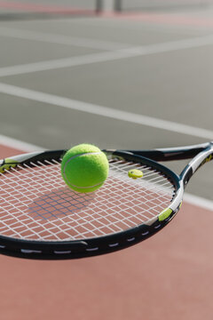 Tennis ball resting on a racket against a blurred court background