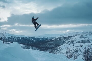 Snowboarder soaring, snowy mountains, winter sky.