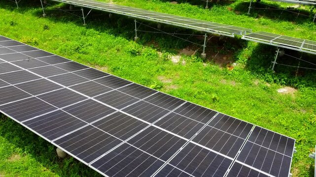 Aerial low closeup rotating view of new shiny bifacial solar panels at Jambur solar park