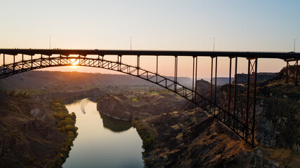 Obraz premium A bridge spans a river with a sunset in the background