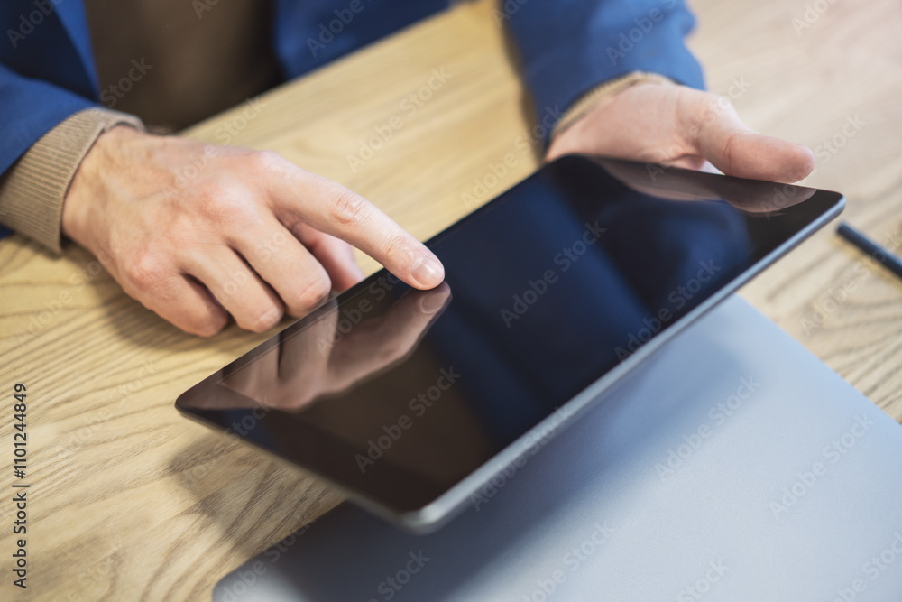 Poster closeup of a man's finger making contact with a state-of-the-art tablet screen, device resting on a 