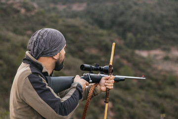 Hunter aiming with rifle in the mountain during hunting season