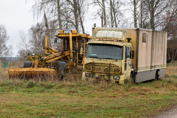 Old yellow truck and yellow road machine