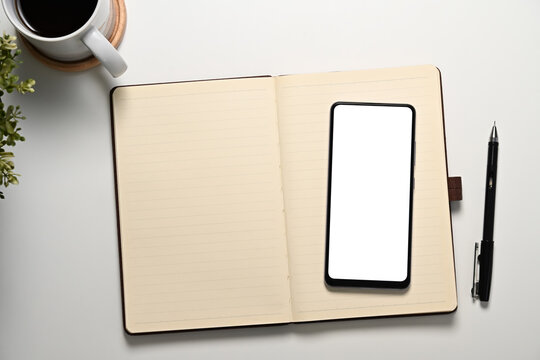 Minimalist office desk with blank smartphone screen, notebook and coffee cup