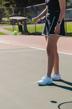 Tennis player bouncing a ball with a racket on a sunny court