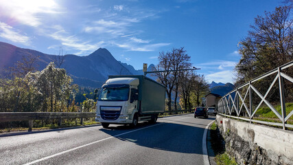 A truck drives through a scenic mountain road in autumn, highlighting transportation and logistics efficiency during peak holiday travel