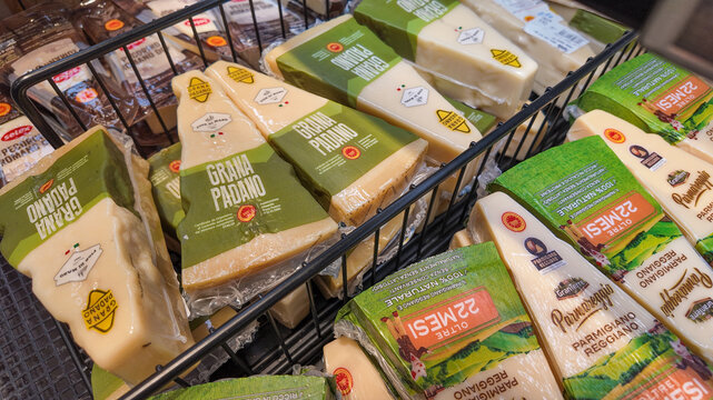 A selection of packaged Italian cheeses, including Grana Padano and Parmigiano Reggiano, displayed in a supermarket basket, ideal for gourmet Italian cuisine and celebrations   14 November 2024, Bellu