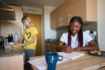 Multiethnic students sharing apartment and studying while cooking