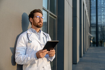 Ginger young doctor in eyeglasses looking serious and thoughtful