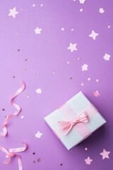 Fototapeta premium Purple Christmas background with gift present box with ribbon and stars