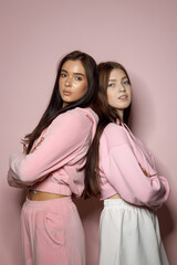 Two Young Women Embracing Individuality With Stylish Outfits Against a Soft Pink Backdrop