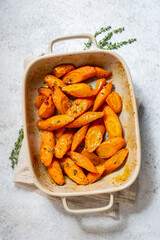 A white dish filled with orange carrots and herbs