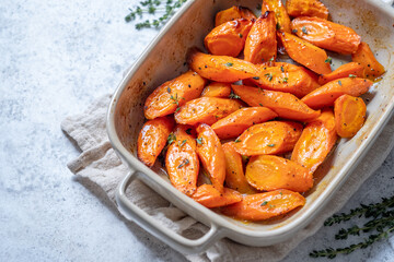 A white dish filled with orange carrots and herbs