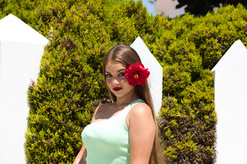 portrait of young and beautiful Latin woman with long blond hair and perfect skin dressed in green,...