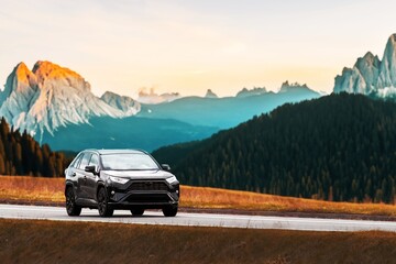 modern family SUV car journeys along a scenic road with majestic nature and a golden sunset in the backdrop. Subcompact truck with more offroad capabilities and 4WD © AlexGo