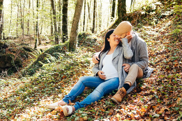 Happy Multiethnic Pregnant Couple Enjoying Nature in a Serene Forest Setting During Autumn