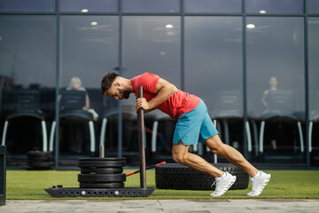Side view of a strong muscular sportsman pushing exercise machine during his strength training.
