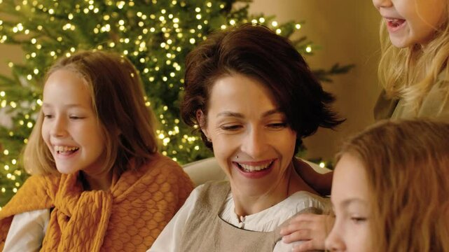 Mom reading the Nativity story in the Bible to her children and discussing it with them on Christmas eve. Famity traditions. Story time.