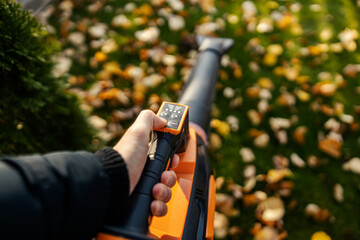 Close up of hand using electric leaf blower in backyard for gardening.