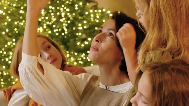 Mom reading the Nativity story in the Bible to her children and discussing it with them on Christmas eve. Famity traditions. Story time.