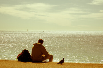 Fototapeta premium Defocused person sitting on the beach looking into the distance