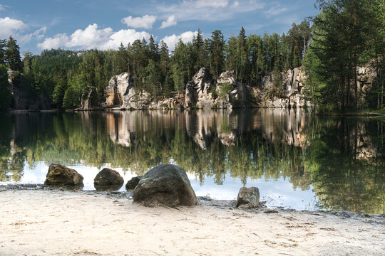 Dramatic rock formations and forest reflected in a rural lake, Adrspach, Hradec Kralove, Czech Republic