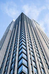 Fototapeta premium Multi-storey building with windows, view from below, clouds in the sky
