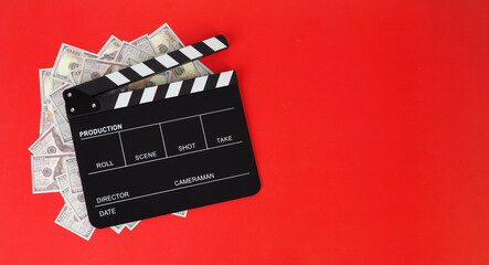 Clapper board and us dollar banknotes on red background