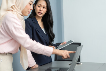 Professional business discussion between two female colleagues using tablet in modern office, teamwork collaboration, diverse workplace, technology in business, professional attire, strategic planning