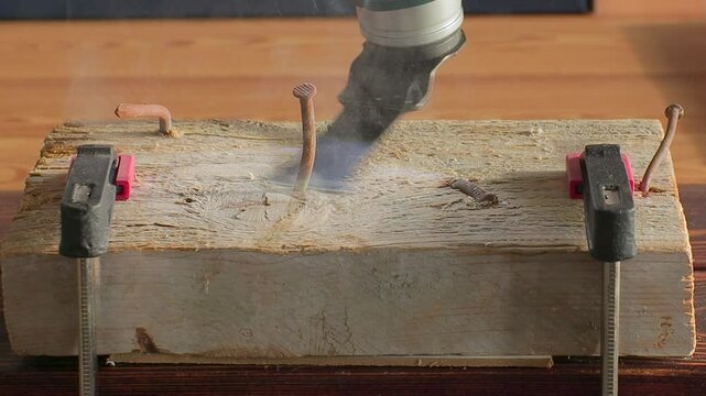 A specialized multi cutter tool showcases its precision while working on a securely clamped wood block with protruding nails