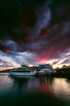 Dramatic grey storm clouds at sunset over boats moored along waterfront, Oslo, Norway