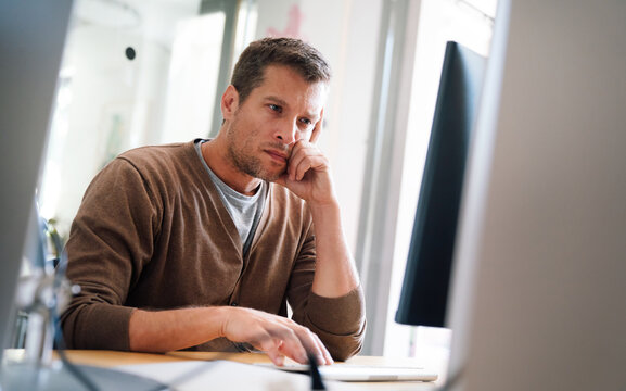 Portrait of a disappointed man programmer looking stressed out while working on a computer code - Powered by Adobe