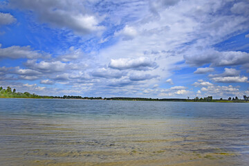  Large blue lake stretches out under a cloudy sky, creating a calm and open atmosphere with distant...