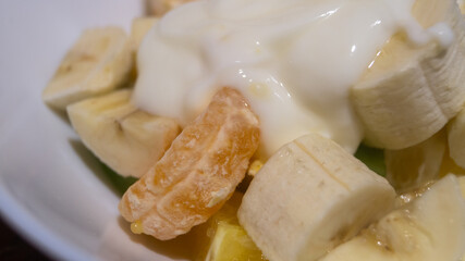 Banana, kiwi, mandarin sliced ​​in a deep plate. Fruit salad with yogurt