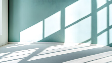Fototapeta premium Sunlight streams through a window, casting shadows on a pale teal wall and white floor. A minimalist, bright and airy interior scene perfect for design or real estate.