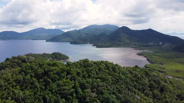 Scenic aerial view rising over tropical island of Pulau Weh with forest trees, mangroves on coastline and volcanic mountainous landscape in Aceh, Sumatra, Indonesia