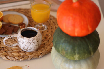 Pumpkins, various food and drinks, fall decorations, books and candles on the table. Fall hygge at home. Selective focus.