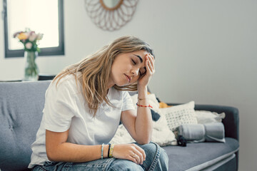 Depressed or tired teen girl feeling stress headache hurt pain sitting alone at home, upset sad...