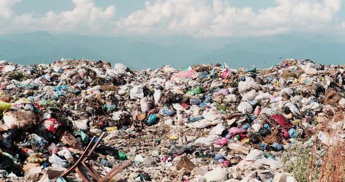 A massive pile of trash with mountains in the background under a bright sky