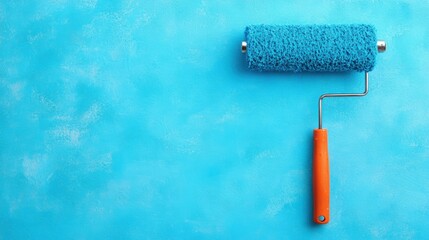 Fototapeta premium A blue paint roller rests on a bright textured wall surface, prepared for a decorating task in a creative space